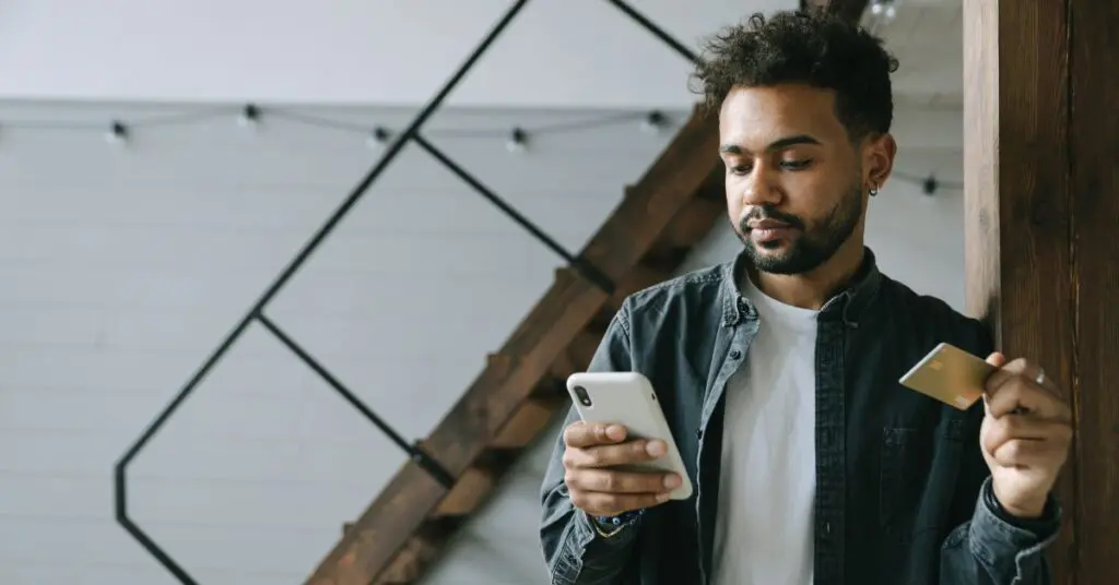 A newcomer in a modern Ontario apartment using a mobile phone and credit card to build their Canadian credit history from zero.
