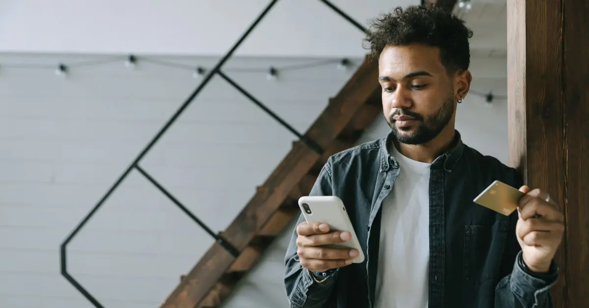 A newcomer in a modern Ontario apartment using a mobile phone and credit card to build their Canadian credit history from zero.