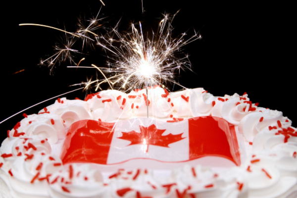 A cake is decorated with a Canadian flag and a sparkler to celebrate Canada Day 2024.