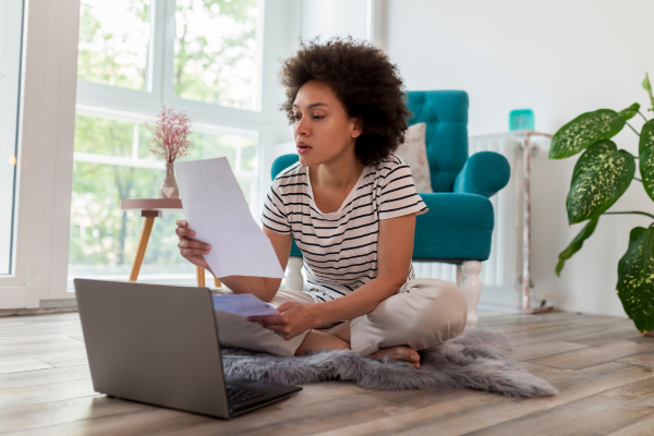 A Canadian homeowner sits on the floor with her laptop working on how to pay her mortgage and whether becoming a homesharing host  and renting out a spare room can help her financially.