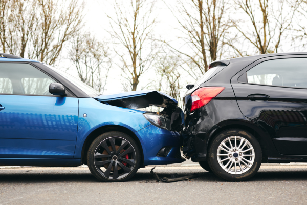 Two cars involved in a traffic accident on the side of the road with damage to both cars. 