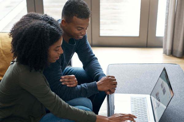 A young couple are looking at a computer and researching short term rentals in Toronto from abroad.