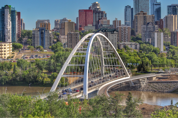 The skyline of the city of Edmonton appears behind the Walterdale Bridge, a through arch bridge spanning the North Saskatchewan River.