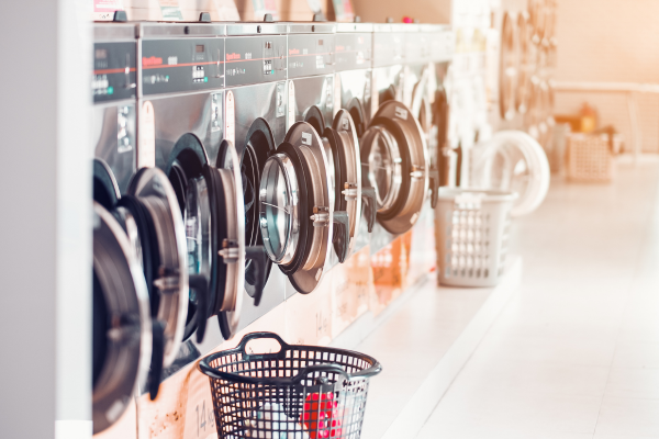 Row of industrial washing machines in a public laundromat with clothes baskets. Basement apartments may not have washer and dryers.