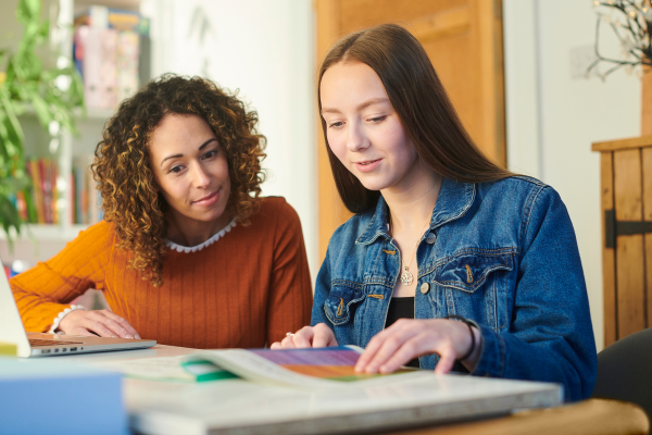 A homestay host in engaging with an international student and looking at a book. 