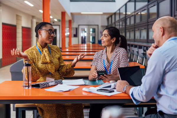 Part of teaching jobs in Canada in Canada is preparing creative lesson plans and curriculum development. Teachers are discussing lessons plans in a classroom.