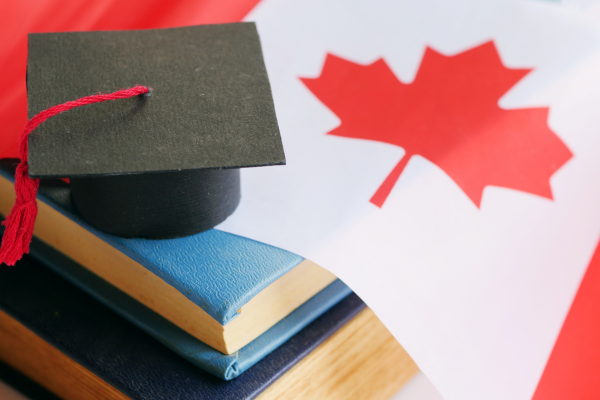 Graduation cap on stack of books with a Canadian flag.