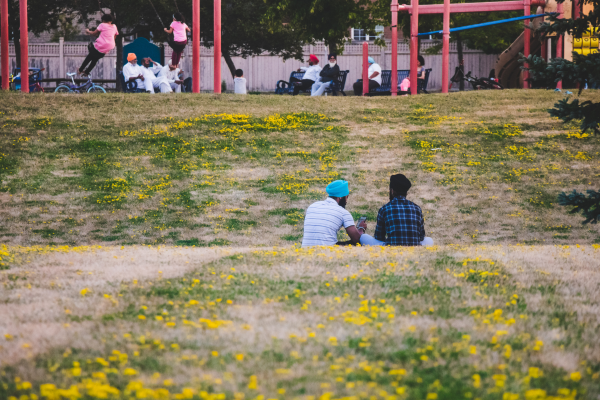 Two men sitting on the lawn in a park in Brampton, Ontario.
