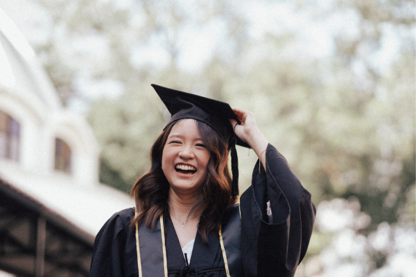 A young woman is wearing a mortarboard at graduation.