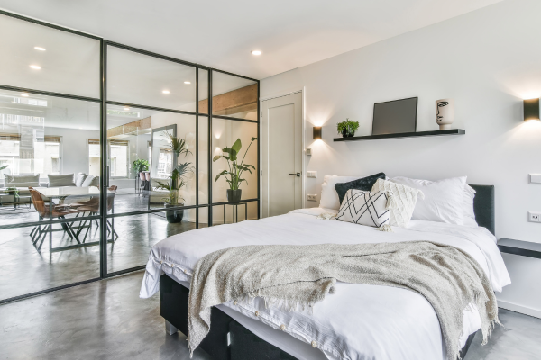 A tastefully decorated white bed rests beside a full-wall mirror in a 2-bedroom apartment.