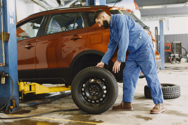 A mechanic is installing winter tires on a car to improve control when driving.