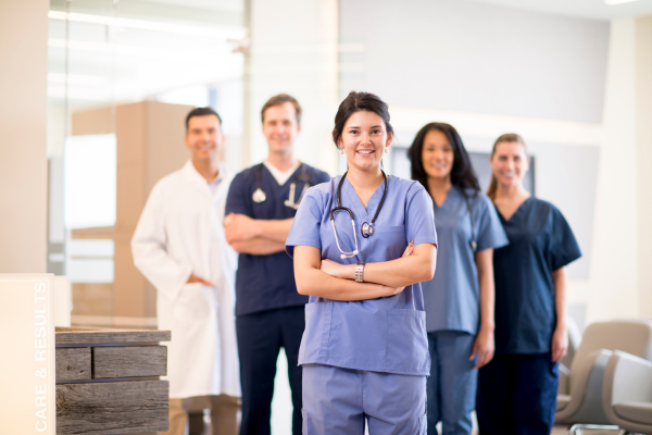 A group of doctors, nurses, dentists, and professional assistants pose for a picture in a medical office. 